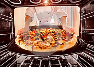 Cocinero cocinando una hoja circular grande de masa ligera en horno 