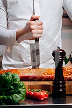 Chef cooking raw meat in the kitchen. chef holds a professional kitchen knife. Concept of Cooking process and preparing dishes