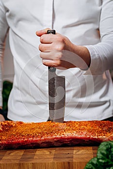 Chef cooking raw meat in the kitchen. chef holds a professional kitchen knife. Concept of Cooking process and preparing dishes