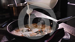 Chef cooking shrimps - add cooking cream