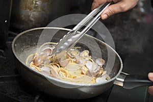 Chef is cooking spaghetti alla vongole