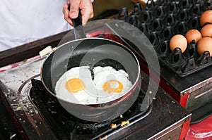 A chef is cooking sunny-side up eggs