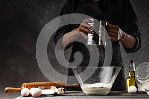 Chef cooks dough. With flour frozen in motion. Against the background of ingredients. Cooking flour products, bread, Italian pasta