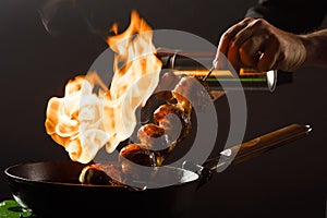 Chef cooks mushrooms in a frying pan with open fire.