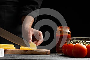 The chef cooks pizza, cut pineapple, on the background with ingredients. Recipe book, menu, home cooking