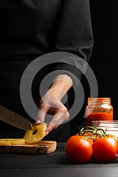 The chef cooks pizza, cut pineapple, on the background with ingredients. Recipe book, menu, home cooking