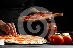 The chef cooks pizza, lays fresh tomatoes, on a background with ingredients. Recipe book, menu, home cooking