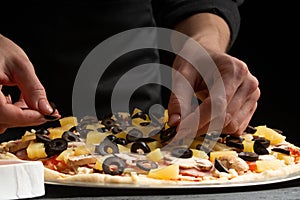 Chef cooks pizza, puts olives on the background with ingredients. Recipe book, menu, home cooking, pizzeria. Macro, close-up