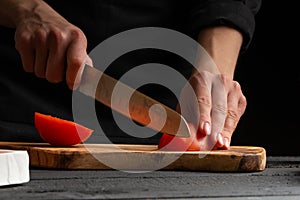 Chef cooks pizza, slices fresh tomatoes, on the background with ingredients. Recipe book, menu, home cooking. close-up