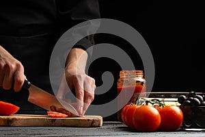 Chef cooks pizza, slices fresh tomatoes, on the background with ingredients. Recipe book, menu, home cooking. Horizontal frame