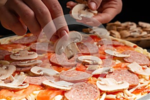 Chef cooks pizza, spreads fresh mushrooms, on the background with ingredients. Recipe book, menu, home cooking. Close up macro