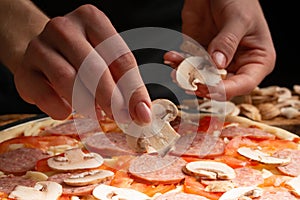 Chef cooks pizza, spreads fresh mushrooms, on the background with ingredients. Recipe book, menu, home cooking. Close up macro