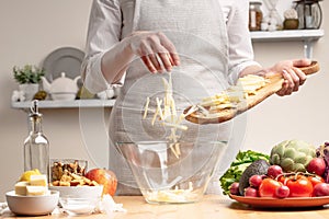 Chef cooks, slices an apple, stir, in the process of a vegetarian salad with the hand of the chef in the home kitchen Light