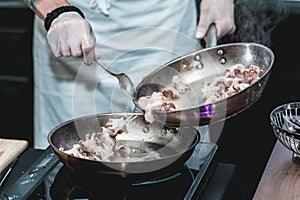 The chef cooks the small octopus on a metal frying pan