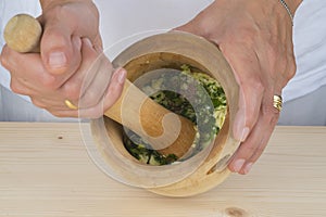 Chef crushing garlic and parsley with mortar and pestle in the k