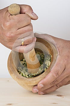 Chef crushing garlic and parsley with mortar and pestle in the k