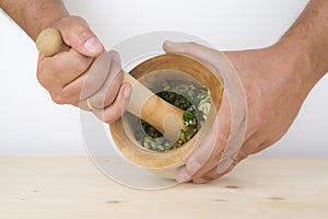 Chef crushing garlic and parsley with mortar and pestle in the k