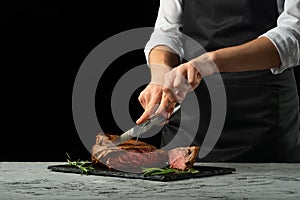 Chef, cut with a meat steak on a black background with an open space for text or restaurant menus. Horizontal photo Black text are