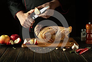 The chef cuts an apple before adding it to a raw duck for roasting in the oven. Cooking a national dish or Peking duck in the