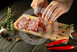 The chef cuts the baked veal meat with a knife for cooking dinner in the kitchen. Fast street food concept on dark background