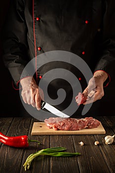 The chef cuts beef raw meat on a cutting board before barbecue. Asian cuisine. Preparing a delicious meal in the kitchen