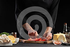 The chef cuts cherry tomatoes to prepare a tasty and fresh salad. Vegetarian and fresh food, gastronomy and cooking, recipe book