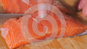 The chef cuts a fillet of fresh red fish with a knife. Cooking salmon raw meat for steak slow motion close up view