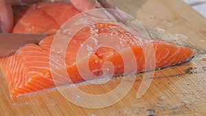 The chef cuts a fillet of fresh red fish with a knife. Cooking salmon raw meat for steak slow motion close up view