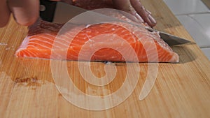 The chef cuts a fillet of fresh red fish with a knife. Cooking salmon raw meat for steak slow motion close up view