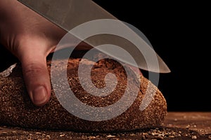 Chef cuts with a knife Whole Fresh fragrant bread on table. Food concept Wheat pastry on cutting board