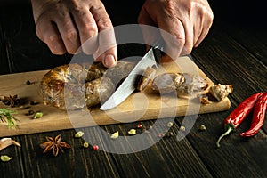 The chef cuts meat sausage with a knife on a cutting kitchen board for a delicious lunch. National dish with veal sausages
