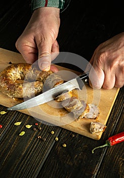 The chef cuts pork sausage on a cutting kitchen board for a delicious lunch. The national dish is sometimes cooked at home