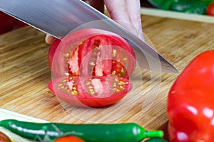 Chef cuts tomatoes into pieces on a cutting Board