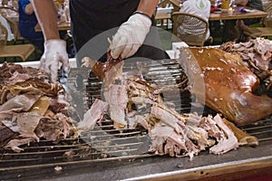 Chef cuts up baked pig pork to serve to guests at buffet