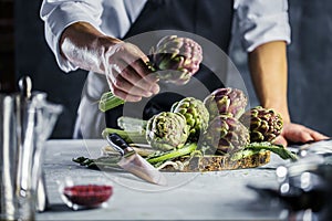 Chef cutting artichokes for dinner preparation - Man cooking inside restaurant kitchen