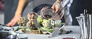 Chef cutting artichokes for dinner preparation - Man cooking inside restaurant kitchen