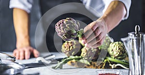 Chef cutting artichokes for dinner preparation - Man cooking inside restaurant kitchen photo