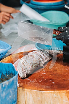 The chef is cutting fish in the kitchen. A chef cuts up fish. Still life on the wooden kitchen board