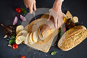 chef cutting Fresh bread on wooden cutting board on kitchen table