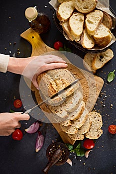 chef cutting Fresh bread on wooden cutting board on kitchen table