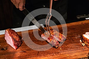 Chef cutting grilled ribs by knife and BBQ fork