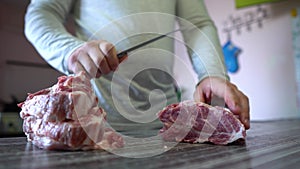 Chef Cutting Meat. Man Cuts Fresh Meat Standing at Table in Kitchen in Bright House. Man Holding Knife in Hand. Food