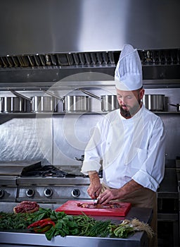 Chef cutting meat in restaurant kitchen