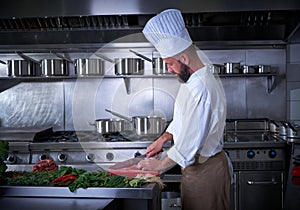 Chef cutting meat in restaurant kitchen