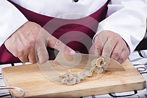 Chef cutting mushroom with knife before cooking