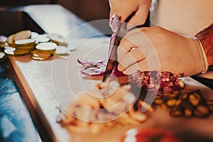 Chef cutting onion with a knife on the board