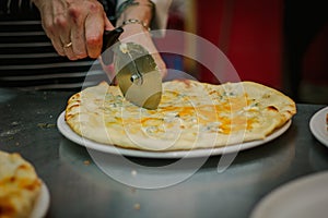 Chef cutting pizza with the round pizza cutter or knife.