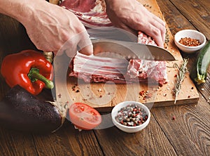 Chef cutting rack of lamb on wooden board