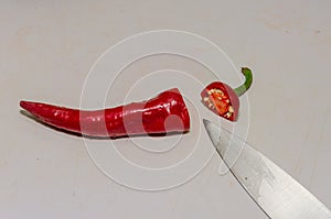 Chef cutting red chili pepper with knife