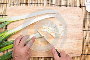 Chef cutting scallion on wooden broad